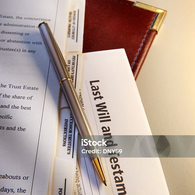Dokument mit der Aufschrift Testament, darauf ein Stift, darunter weitere beschriebene Dokumente
