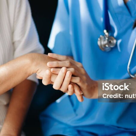 Person in Krankenhauskleidung hält die Hand einer anderen Person