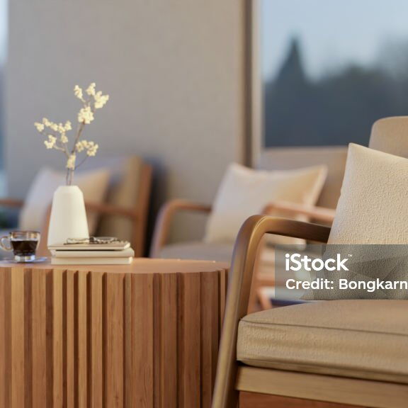 ein leerer Sessel, mit Beistelltisch auf welchen ein Kaffee und Blumen stehen